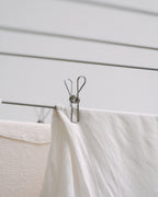 Forever Pegs marine-grade stainless steel peg holding a white sheet on a clothesline