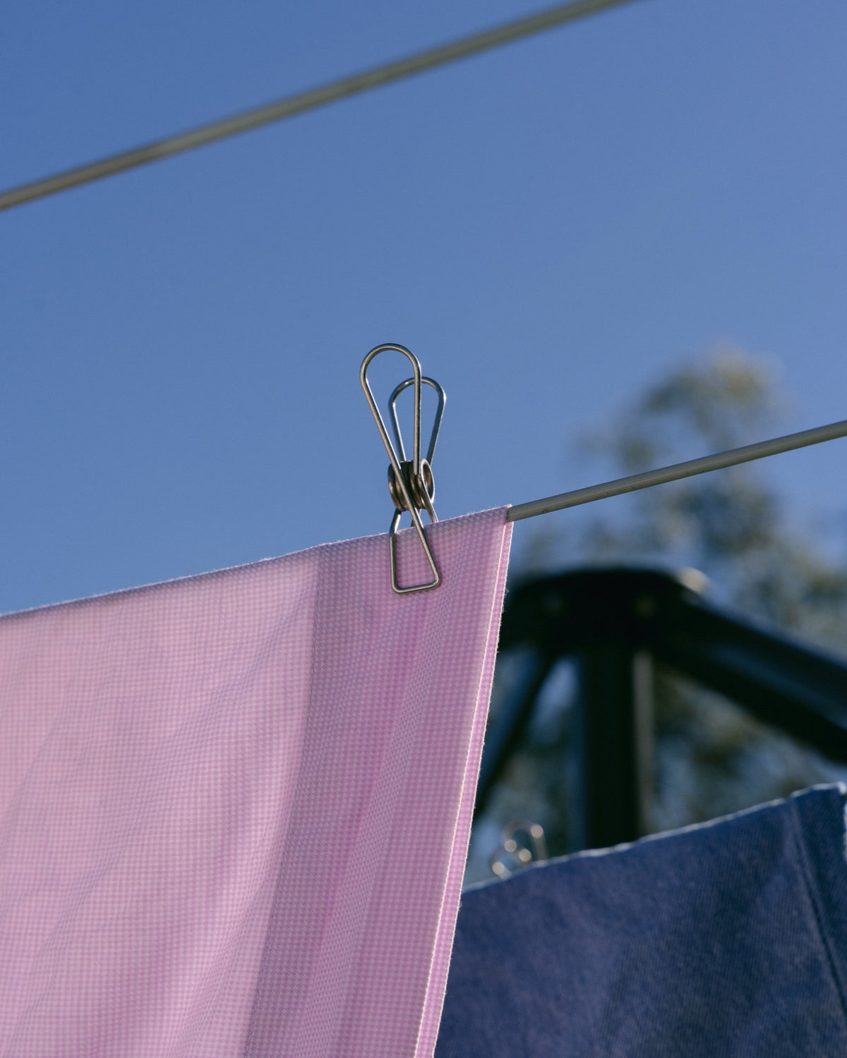 Forever Peg holding a pink towel against a blue sky