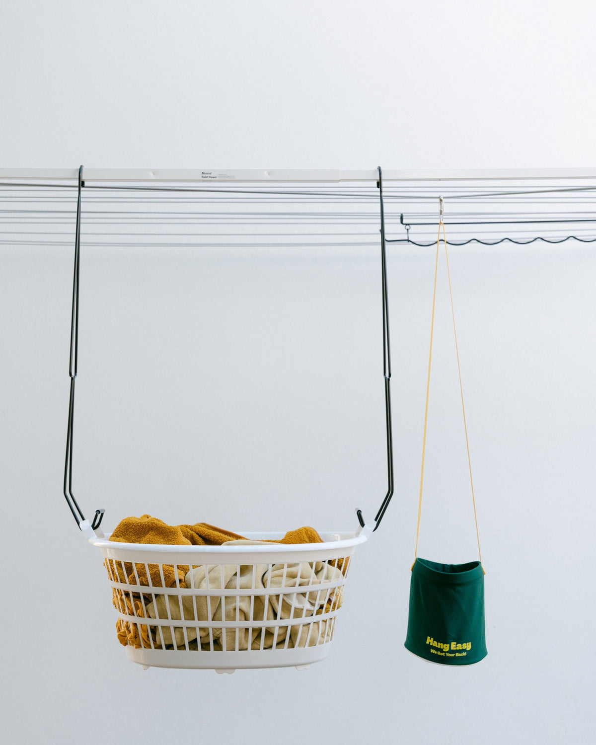Hang Easy Basket Hangers holding a white washing basket at waist height on a clothesline