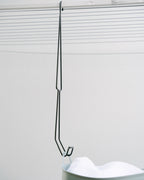 A full-length Hang Easy Basket Hanger hooked on the clothesline frame and holding a basket handle