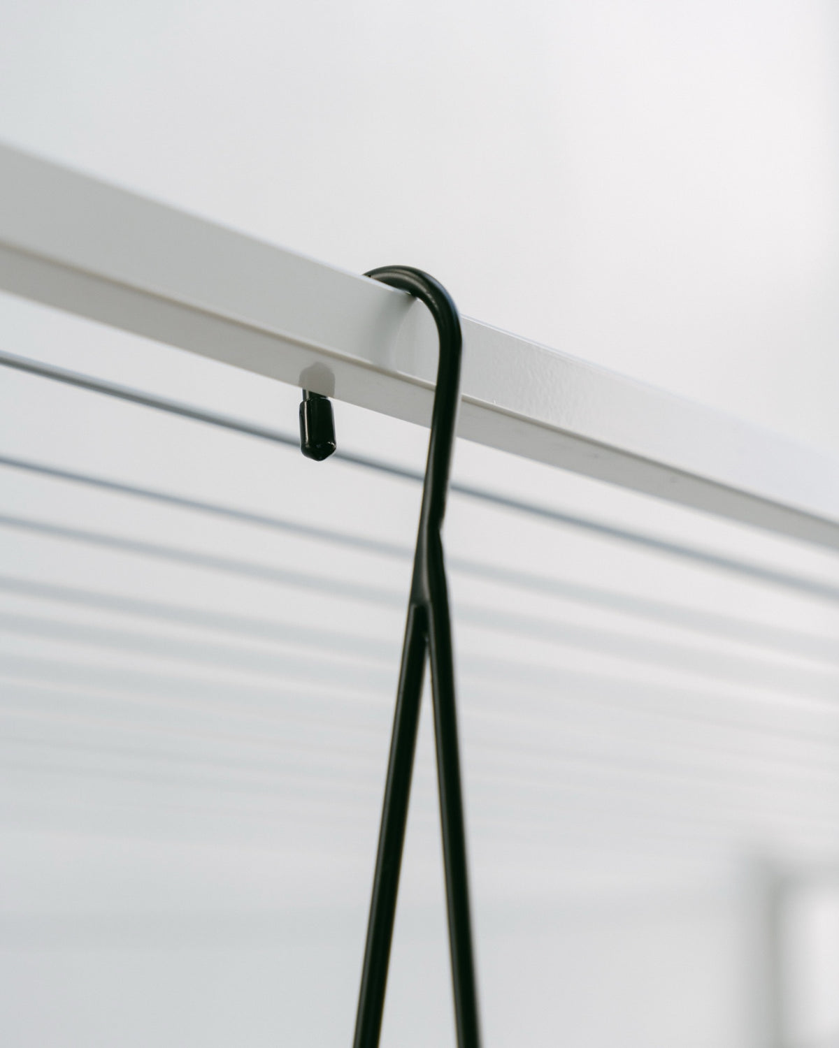 Hang Easy Basket Hanger hooked over the metal bar of a folding clothesline