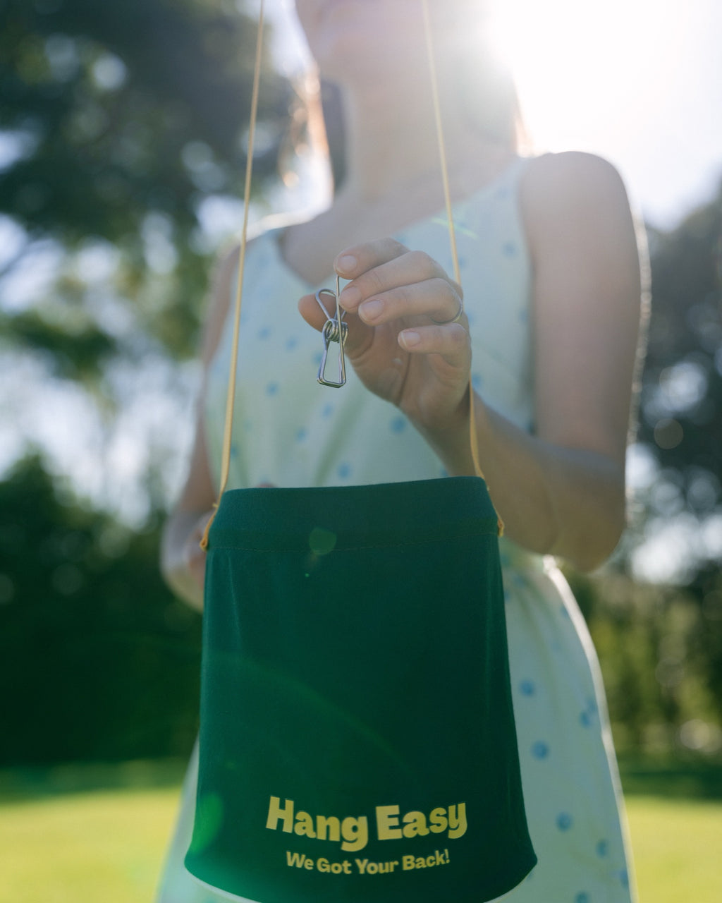 Woman reaching into the Hang Easy Peg Bag for a peg in a sunny backyard