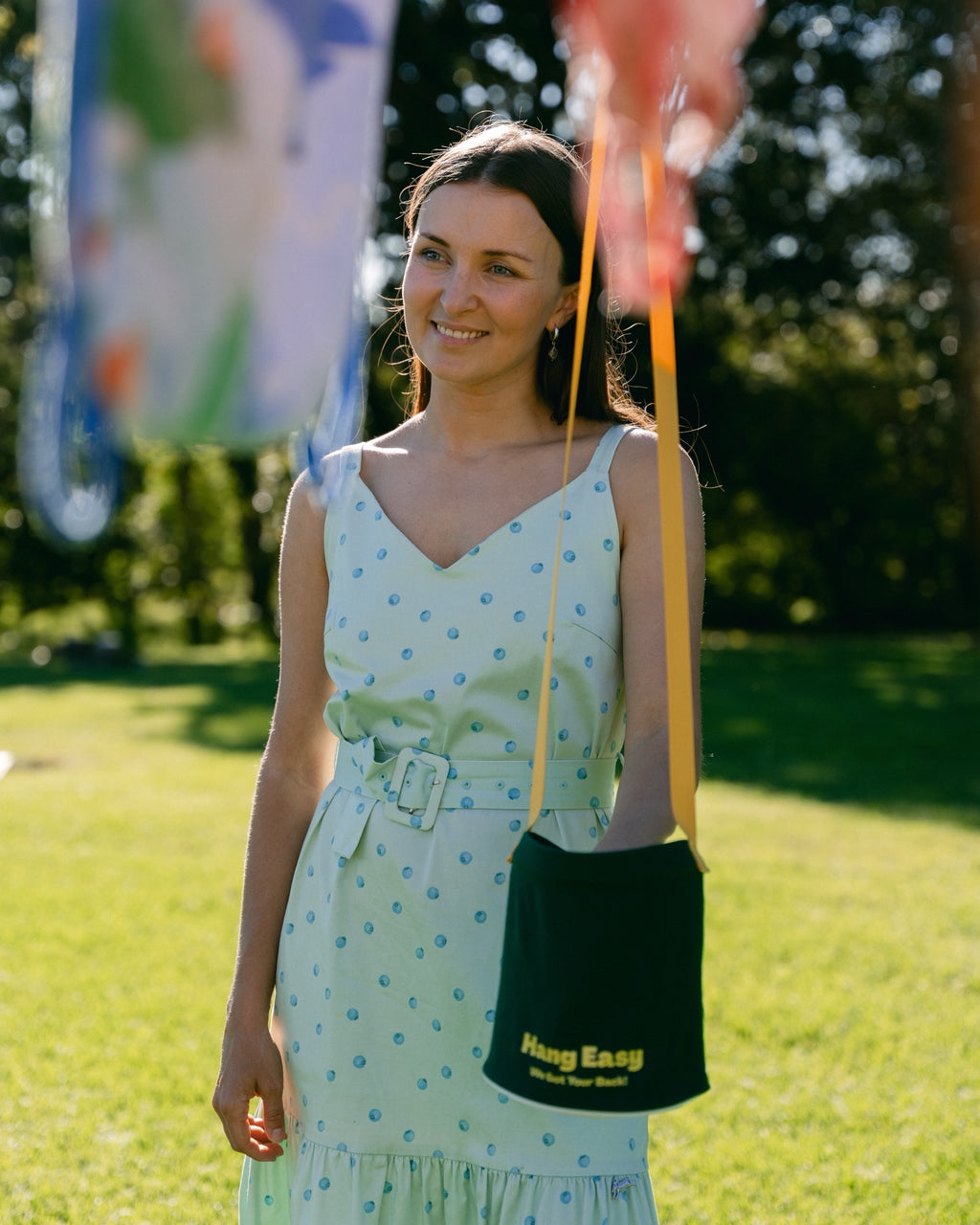 Smiling woman in a sunny backyard with the Hang Easy Peg Bag hanging at hip height