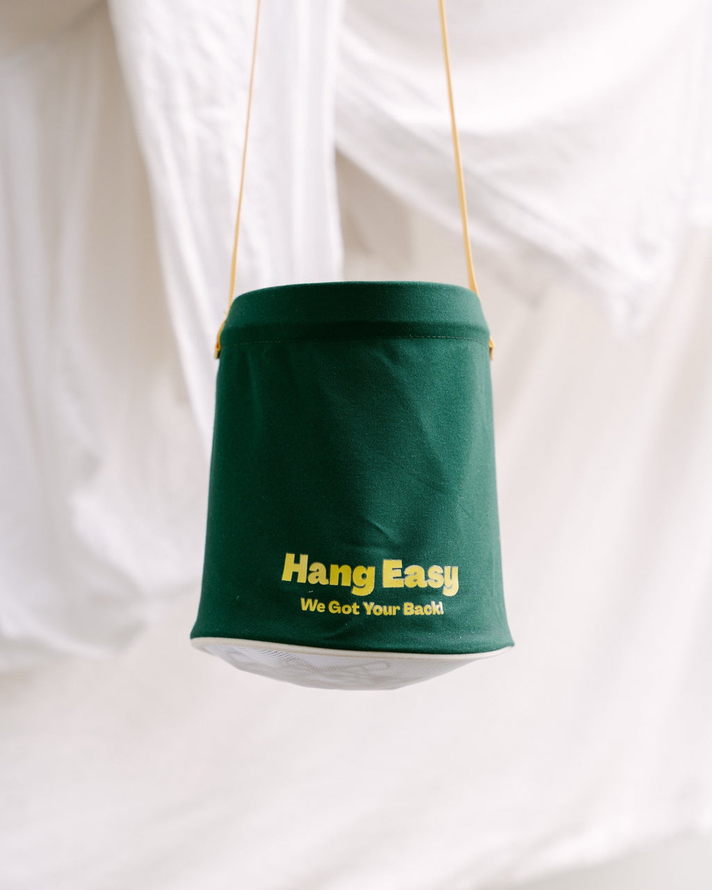 Green Hang Easy Peg Bag hanging in front of fresh white sheets on the clothesline