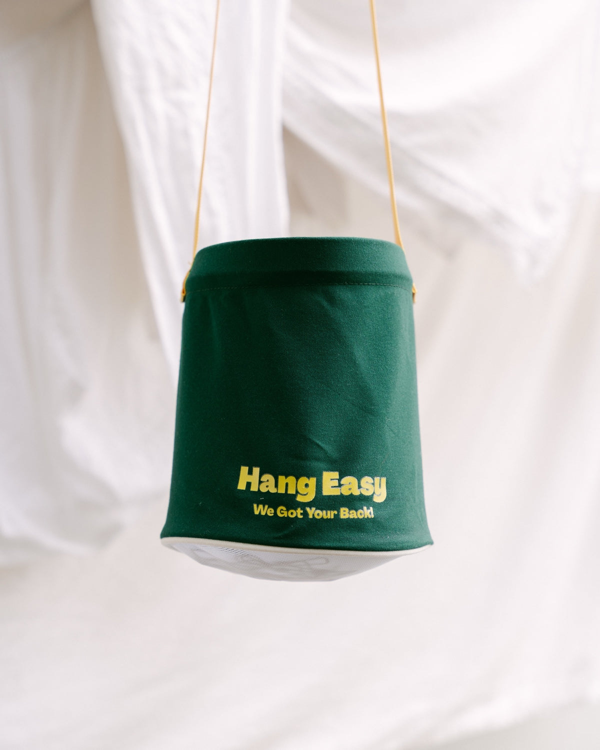 Green Hang Easy Peg Bag hanging in front of fresh white sheets on the clothesline